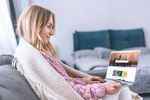 Attrayant femme blonde en utilisant un ordinateur portable avec le site shutterstock à l'écran et tenant la carte de crédit — Photo de stock