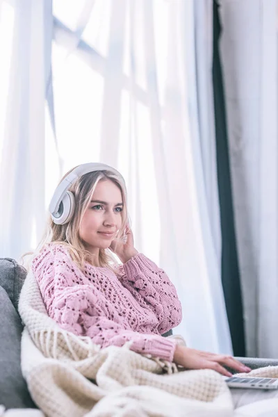 Mujer rubia escuchando música en auriculares en casa - foto de stock