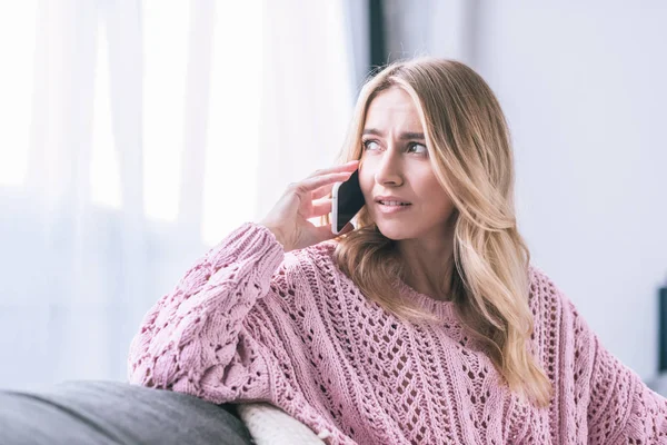 Atractiva mujer rubia hablando en el teléfono inteligente en casa - foto de stock