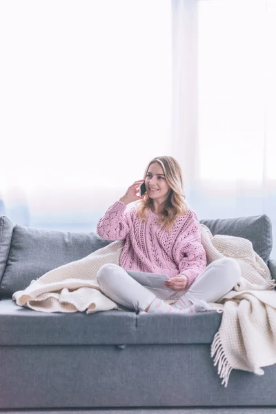 Atractiva mujer rubia hablando en el teléfono inteligente en casa - foto de stock