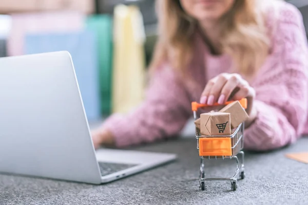Selective focus of toy cart with small paper boxes with woman on background — Stock Photo
