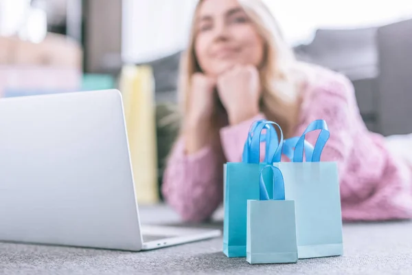 Foco selectivo de bolsas de compras con mujer de ensueño en el fondo - foto de stock