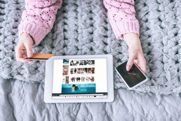 Vista ritagliata di donna in possesso di carta di credito e smartphone vicino tablet digitale con amazon app sullo schermo — Foto stock