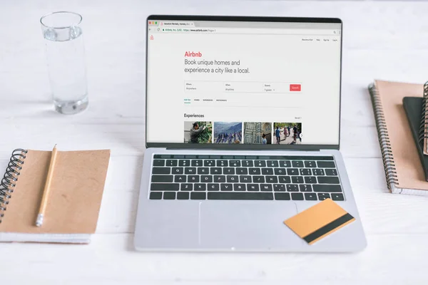 Laptop with Airbnb website on screen and credit card on wooden desk — Stock Photo