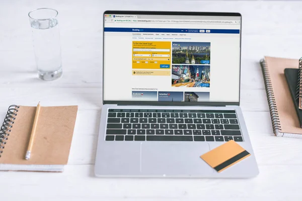 Laptop with Booking website on screen and credit card on wooden desk — Stock Photo