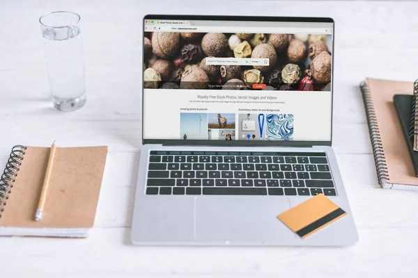 Laptop with depositphotos website on screen and credit card on wooden desk — Stock Photo