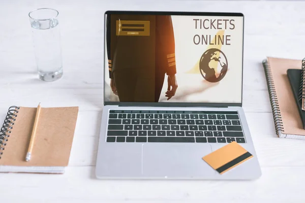 Computer portatile con biglietti sito online sullo schermo e carta di credito sulla scrivania in legno — Foto stock