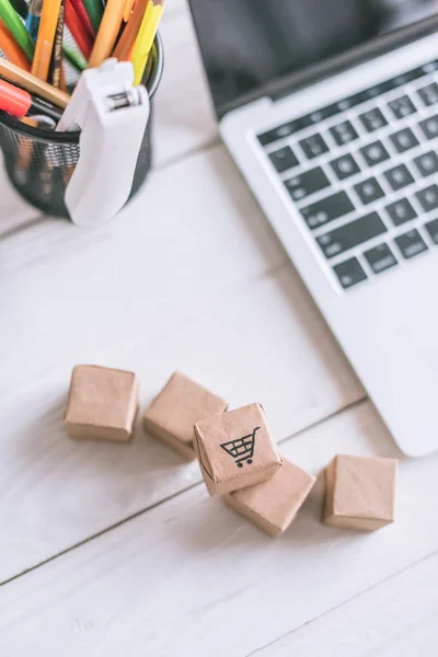 Vue de dessus des paquets dans le chariot près de l'ordinateur portable et de la papeterie sur le bureau en bois — Photo de stock