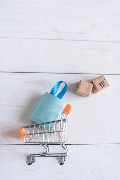 Close up of packages and shopping bag near toy cart on wooden desk — Stock Photo