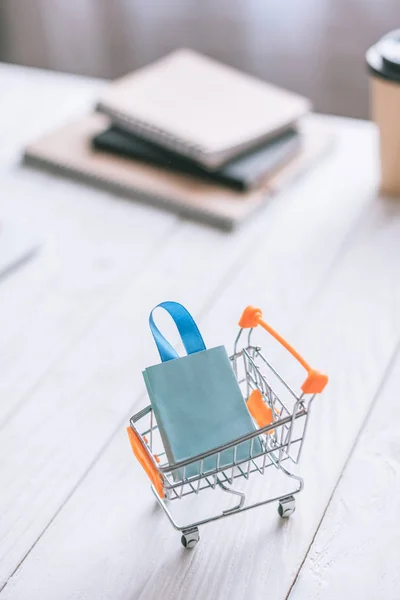 Selective focus of decorative shopping bag in cart on wooden desk — Stock Photo