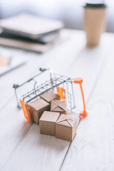 Selective focus of toy of packages near decorative cart on wooden desk — Stock Photo