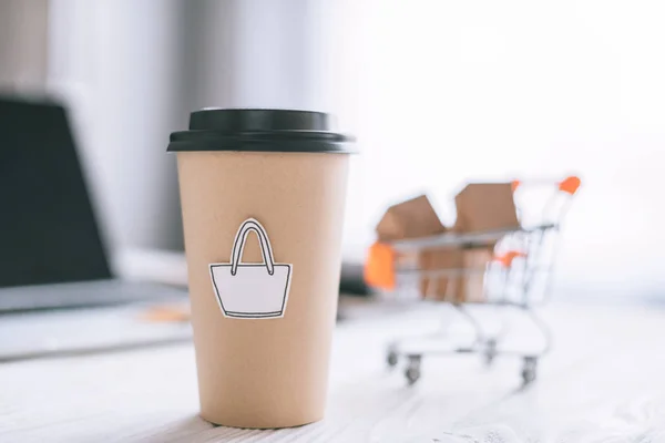 Foyer sélectif de tasse en papier avec symbole près du chariot à jouets avec boîtes — Photo de stock