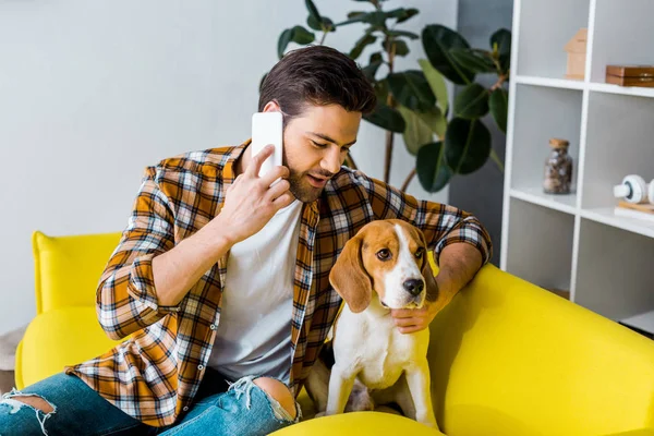 Молодий чоловік розмовляє по смартфону і дивиться на собаку — стокове фото