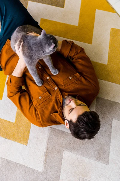 Top view of handsome man lying on carpet with british shorthair cat — Stock Photo