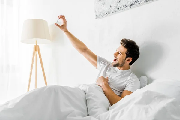 Aufgeregter Mann macht Selfie mit Smartphone im Schlafzimmer — Stockfoto