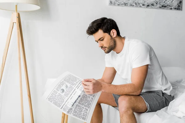 Красивий молодий чоловік читає газету в спальні — стокове фото