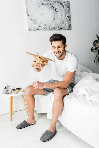 Happy man playing with wooden toy plane in bedroom — Stock Photo