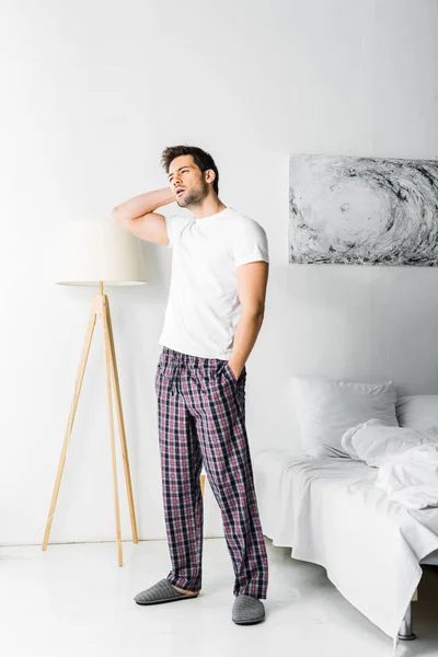 Уставший мужчина в пижаме смотрит в спальню по утрам — стоковое фото