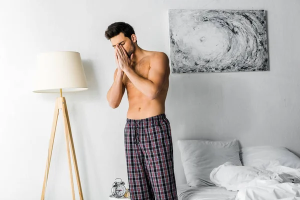 Безсоромний чоловік з головним болем, що стоїть у спальні — стокове фото