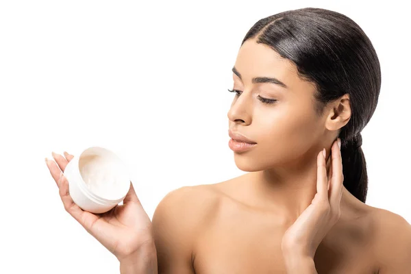 Atractiva joven afroamericana mujer sosteniendo contenedor con crema aislada en blanco - foto de stock