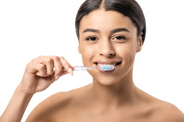Heureuse jeune femme afro-américaine brossant les dents et regardant la caméra isolée sur blanc — Photo de stock