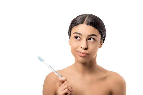Reflexiva chica afroamericana desnuda sosteniendo el cepillo de dientes y mirando hacia otro lado aislado en blanco - foto de stock