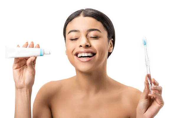 Happy naked african american girl holding toothbrush with toothpaste and laughing isolated on white — Stock Photo
