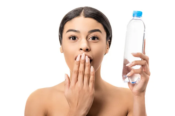 Scioccato giovane donna afroamericana in possesso di una bottiglia d'acqua e guardando la fotocamera isolata su bianco — Foto stock