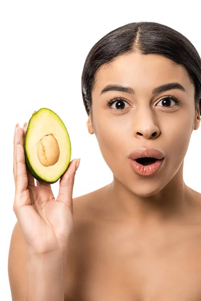 Здивований молода жінка тримає авокадо і дивлячись на камеру, ізольовані на білому — стокове фото