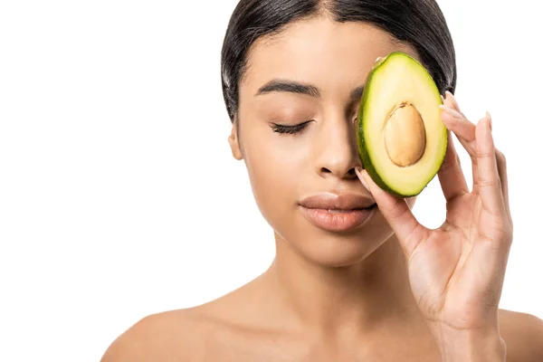 Schöne junge afrikanisch-amerikanische Frau hält die Hälfte der Avocado in der Nähe Gesicht isoliert auf weiß — Stockfoto