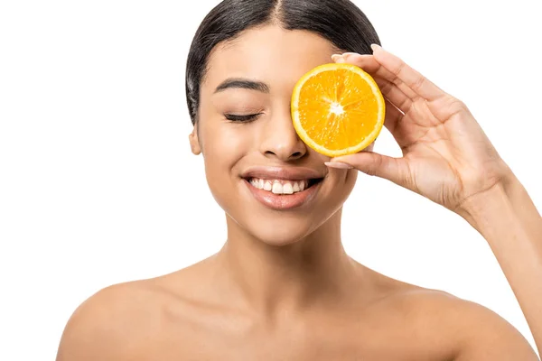 Красива усміхнена афроамериканська дівчина тримає шматочок апельсина біля обличчя ізольовано на білому — стокове фото