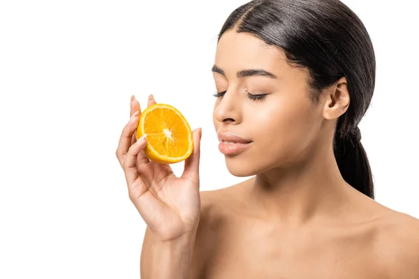 Beautiful naked african american woman with closed eyes holding half of orange near face isolated on white — Stock Photo