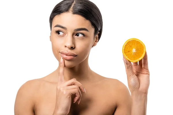 Вдумчивая африканская американка держит половину апельсина и смотрит в сторону изолированных на белом — стоковое фото
