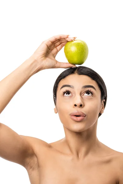 Hermosa chica afroamericana desnuda sosteniendo manzana verde en la cabeza y mirando hacia arriba aislado en blanco - foto de stock