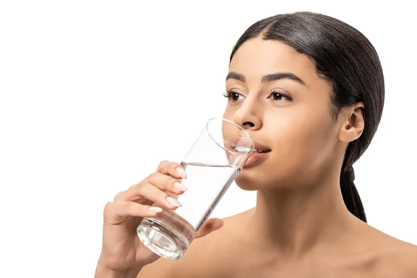 Hermosa joven afroamericana mujer bebiendo agua de vidrio y mirando hacia otro lado aislado en blanco - foto de stock