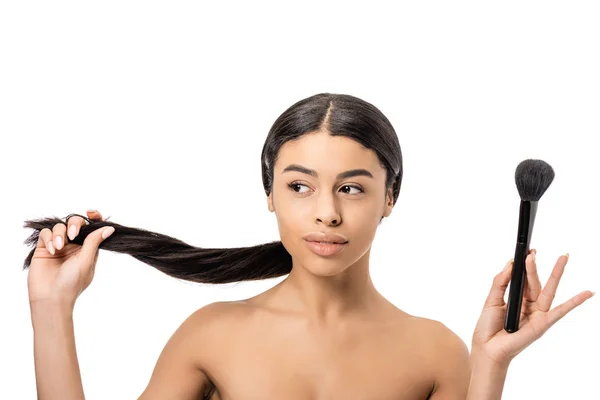 Attrayant nu afro-américain femme tenant brosse de maquillage et cheveux bruns isolés sur blanc — Photo de stock