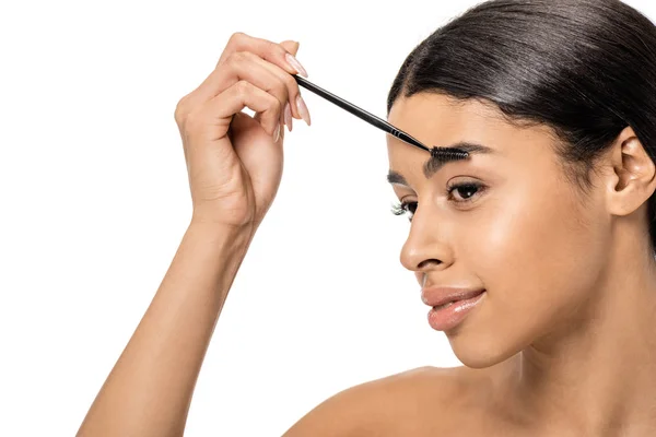 Beautiful smiling brunette african american girl correcting eyebrow with brush isolated on white — Stock Photo
