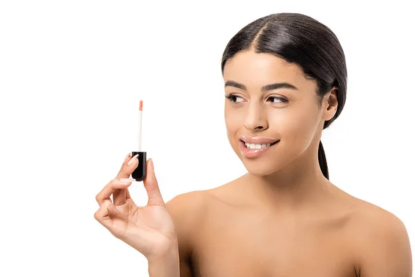 Hermosa sonriente mujer afroamericana desnuda sosteniendo el cepillo de brillo de labios y mirando a un lado aislado en blanco - foto de stock