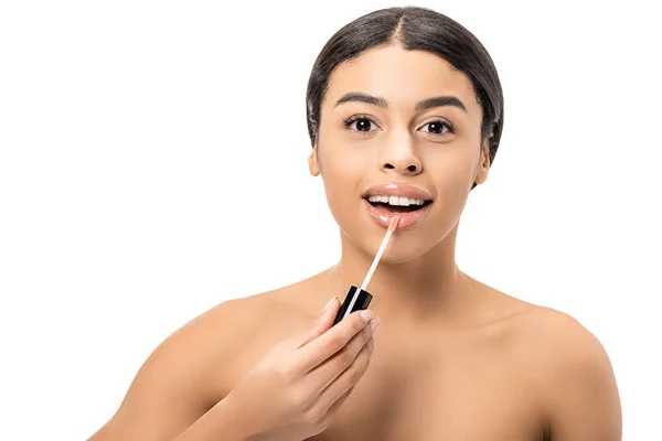 Hermosa mujer afroamericana desnuda aplicando brillo de labios y sonriendo a la cámara aislada en blanco - foto de stock