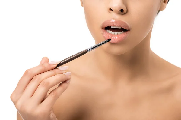 Abgeschnittene Aufnahme einer nackten jungen afrikanisch-amerikanischen Frau, die Lippenstift mit Kosmetikpinsel isoliert auf weiß aufträgt — Stockfoto
