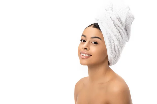 Hermosa mujer afroamericana desnuda con toalla en la cabeza sonriendo a la cámara aislada en blanco - foto de stock