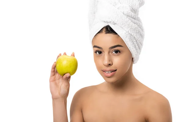 Hermosa joven afroamericana mujer con toalla en la cabeza sosteniendo manzana fresca y sonriendo a la cámara aislada en blanco - foto de stock