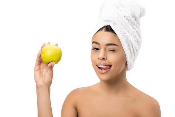 Heureuse jeune femme afro-américaine avec serviette sur la tête tenant pomme fraîche et clin d'oeil à la caméra isolée sur blanc — Photo de stock