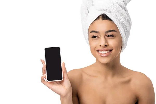 Красива щаслива молода афроамериканська жінка з рушником на голові тримає смартфон з порожнім екраном ізольовано на білому — стокове фото