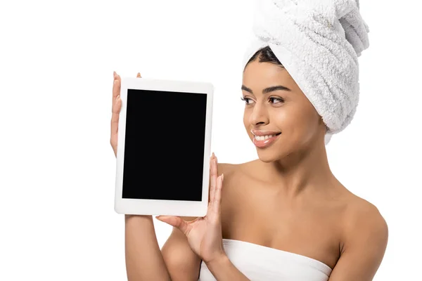 Красива усміхнена молода афроамериканка з рушником на голові тримає цифровий планшет з порожнім екраном ізольовано на білому — стокове фото