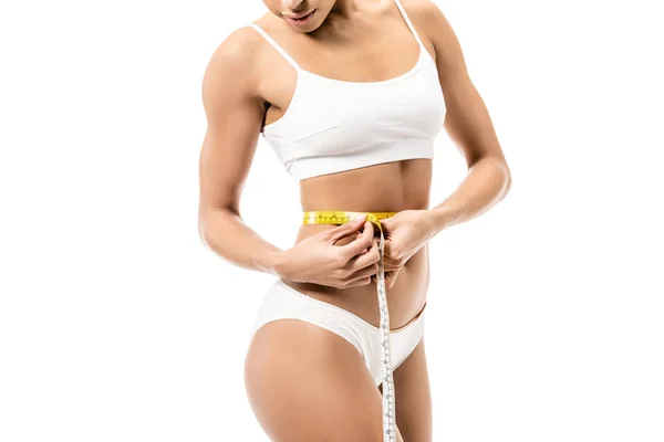 Cropped shot of young african american woman in underwear measuring waist with tape isolated on white — Stock Photo