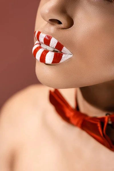 Обрезанный снимок красивых красно-белых полосатых женских губ, изолированных на бордовом — стоковое фото