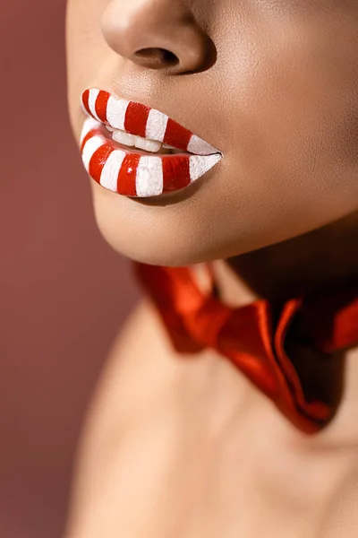 Gros plan vue partielle de belles lèvres féminines rayées rouges et blanches isolées sur bordeaux — Photo de stock