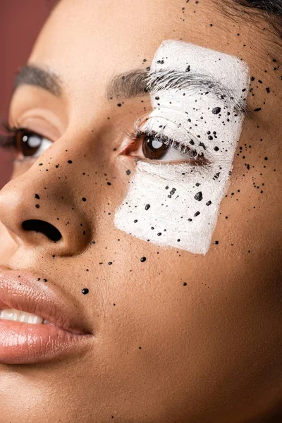 Close-up view of sensual african american woman with creative body art on face looking away isolated on brown — Stock Photo