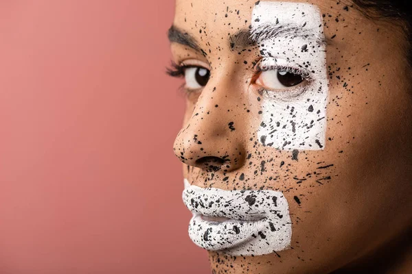 Close-up vista da bela mulher americana africana com tinta branca e marrom no rosto olhando para a câmera isolada em rosa — Fotografia de Stock